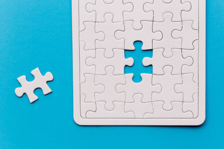 Unfinished white jigsaw puzzle pieces. One missing jigsaw piece on blue background