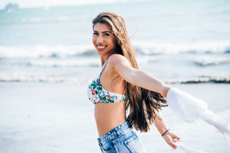 Young attractive and beautiful Caucasian woman posing with white scarf blowing the wind in tropical summer beachの写真素材