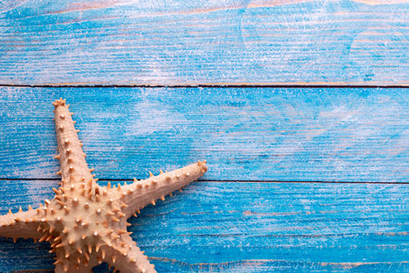 Top view of big starfish on blue wood textured background - with copy space - summer time and...