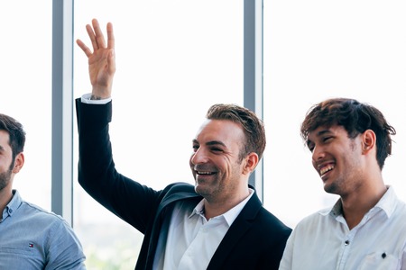 Close-up of senior Caucasian businessman raising hand up alongside with corporate colleagues in seminar discussionの写真素材