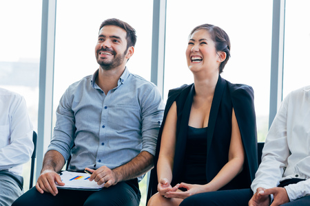 Close-up of businesswoman laughing and having fun listening to presentation and seminar alongside with male business coworkerの写真素材