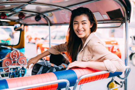 Young Asian female tourist woman exploring Bangkok, Thailand with local tuk tuk taxi and sightseeing...
