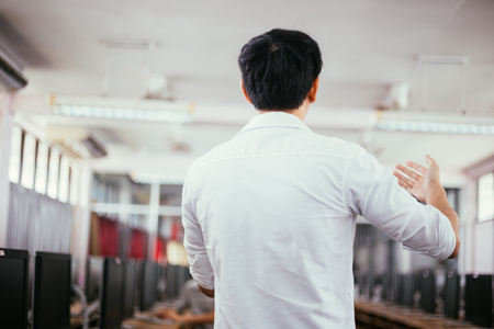 Rear view of male businessman speaking and making a lecture in public speaking event in small roomの写真素材