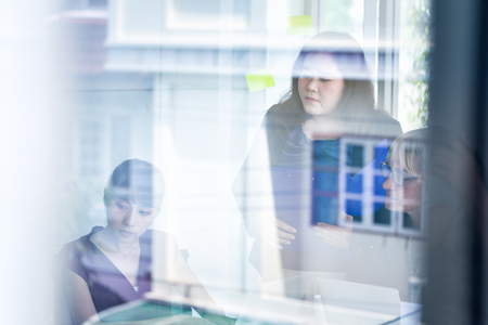 Group of Asian and Caucasian diverse businesswomen holding documents with glass reflection of office buildingの写真素材