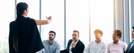 Elegant woman doing presentation for group of modern male coworkers having business meeting in light...