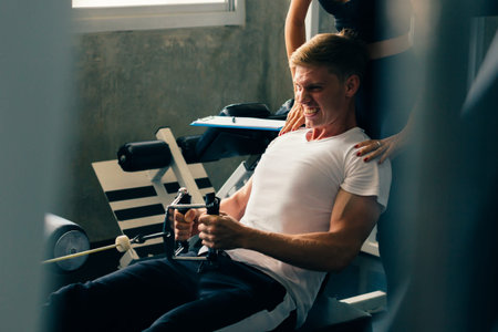 Young Caucasian man in white shirt at a gym, training hard and pulling weights. Lifting heavy...