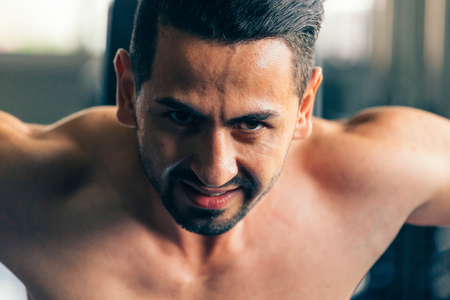 Close-up of young Caucasian furious and angry male fitness muscular model lifting heavy dumbbells. Intense and aggressive workout portrait conceptの写真素材