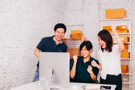 Asian businessman and business women celebrating success and victory in small officeの写真素材