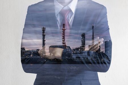 Double exposure image of Business man with petroleum oil refinery plant beside river. Crude Oil Process machineryの写真素材