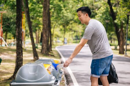 Close up of man hand throwing a plastic bottle into recycle dustbin. Garbage sorting before putting in garbage bin. Save the earth and Environmental concern conceptの写真素材