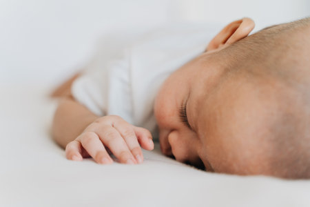 Newborn baby kid sleeping on his stomach on bed at home. Asian child bottom up sleeping position