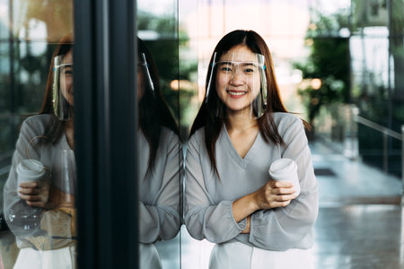 Young 20s Asian beautiful girl wearing a protective face shield and mask. Professional business...