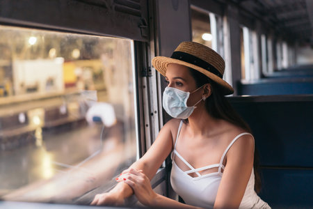 Young brunette woman traveling in Thailand on train during pandemic Coronavirus. 20s Hispanic in a...