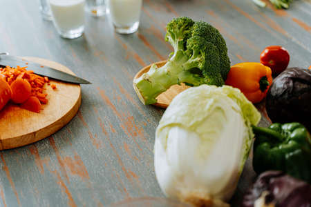 High angle of various ripe vegetables placed near cutting board and knife on table in kitchen during food preparation processの写真素材