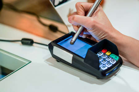 Close up video of womans hand entering information on credit card reader in shopの写真素材