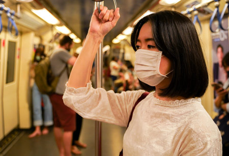 young adult Asian woman wearing a face mask on subway train in Bangkok, Thailand. New normal lifestyle during Covid19 - Coronavirus pandemicの写真素材