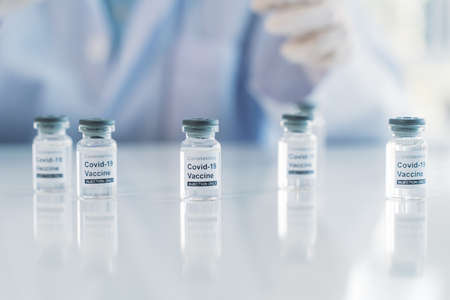 COVID-19 Coronavirus vaccine tubes with medical doctor behind with copy space. Healthcare And Medicine conceptの写真素材
