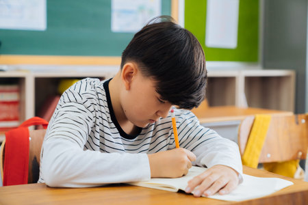 Caucasian school boy sitting in school with pencil, studying, education, learning. Male student...