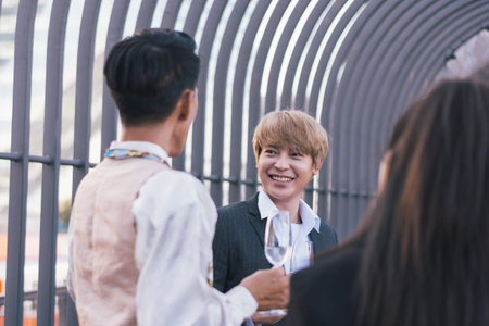 Young business people toasting with each other and smiling while standing on rooftopsの写真素材