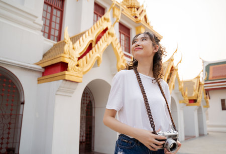 Asian woman tourist backpacker smiling, traveling and taking photo with temple background in Bangkok, Thailand. Asian people excited and having fun traveling.の写真素材