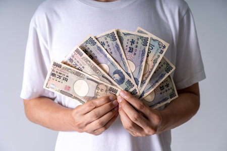 Hands grasping Yen bills in moody lighting: Closeup of 1000 and 10000 notes illustrates financial power and societal tensions in Japanの写真素材