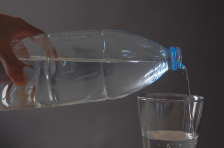 Water pouring into glass over black backgroundの写真素材