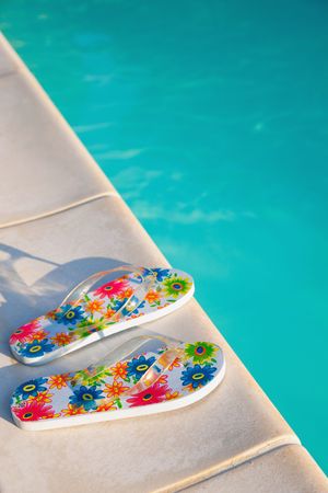 two flip-flops with flowers near the swimming-pool in the morning sunの写真素材