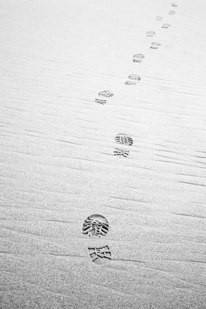 Footprints hiking boots on beach. Monochrome