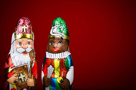 Close up of Sinterklaas and Black Pete . Saint  Nicholas chocolate figure of  Dutch character of Santa Claus on red background.の写真素材