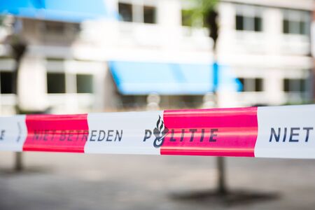 Dutch police line. Do not cross. Red plastic tape on a crime scene.の写真素材