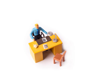 Miniature people businessman sitting behind his work desk. Macro shot from above of Tiny people...