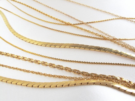 Gold necklace chains in a variety of beautifully crafted links on white satin                               の写真素材