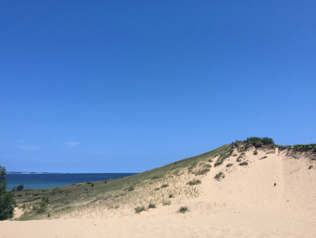 Three People Hiking on a Sand Dune Towards Lakeの写真素材