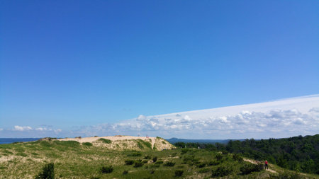 Hikers make it to the top of a large sand duneの写真素材