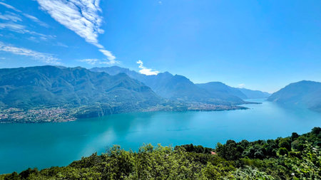 A wide, high-angle shot capturing the stunning blue-green waters of Lake Como as they wind between...