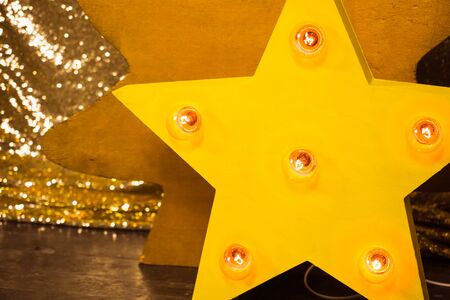 Wooden yellow star with bulb lights lit on it christmas backgroundの写真素材