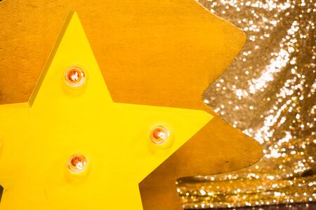 Wooden yellow star with bulb lights lit on it christmas backgroundの写真素材