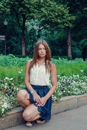 Young attractive brunette dressed skirt and blouse in Moscow summer parkの写真素材
