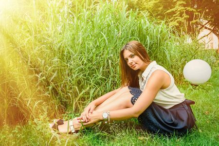 Young attractive brunette dressed skirt and blouse in Moscow summer parkの写真素材