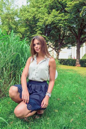 Young attractive brunette dressed skirt and blouse in Moscow summer parkの写真素材