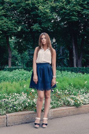Young attractive brunette dressed skirt and blouse in Moscow summer parkの写真素材