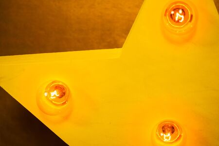 Wooden yellow star with bulb lights lit on it christmas backgroundの写真素材