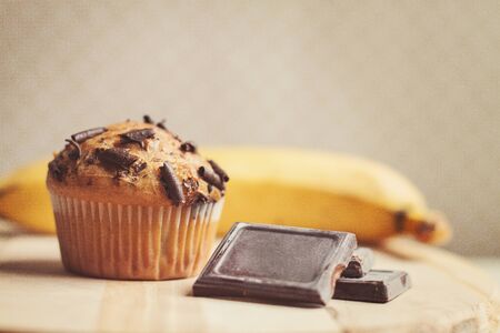 Chocolate banana muffin on the wooden board.  Fresh bananas near it.の写真素材