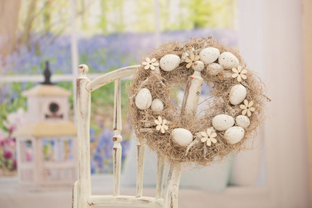 Happy Easter. Wicker egg wreath on a chair indoors.の写真素材