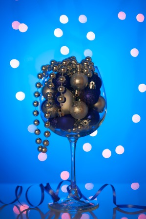 Christmas ornaments in a large wine glass of blueの写真素材