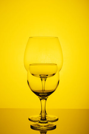 Two empty wine glass on yellow backgroundの写真素材