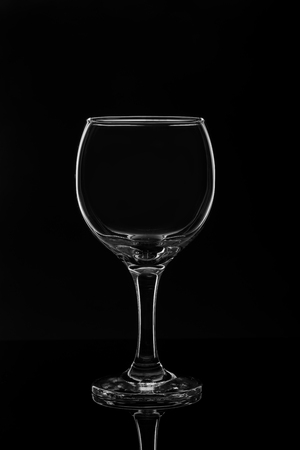 Empty wine glass on black background with reflectionの写真素材