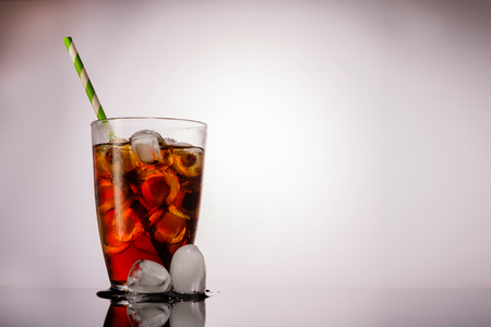 Cola in glass with ice on grey background.の写真素材