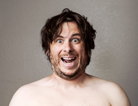 Topless man making a creepy looking smile at the camera against a lightly textured background