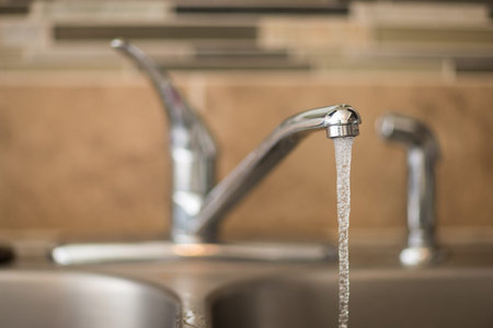 Getting a drink of water from the sink. View has shallow depth of field and is a head on view of a faucetの写真素材